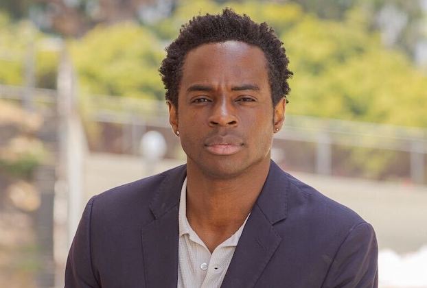 Black man wearing a suit looks straight into the camera 