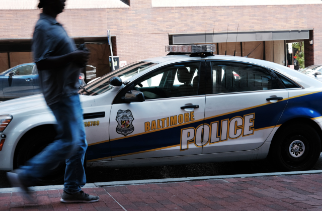 A person walks past a police car on July 28, 2019 in Baltimore, Maryland. 