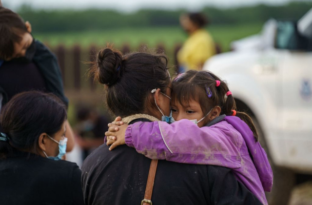A migrant woman holds her daughter while waiting to be processed by the United States Border Patrol