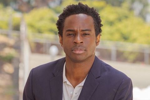 Black man wearing a suit looks straight into the camera 