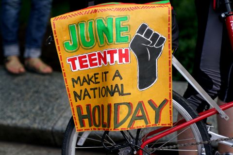 Sign with black fist that reads "Juneteenth Make it a National Holiday