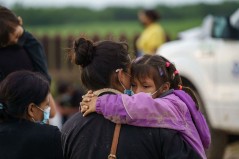 A migrant woman holds her daughter while waiting to be processed by the United States Border Patrol